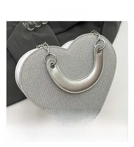 Vue détaillée du sac à main argenté en forme de cœur avec texture tissée métallique