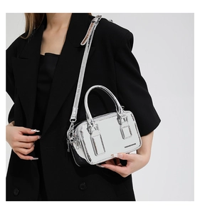 Chic metallic silver crossbody bag held by a model in a black suit for style contrast