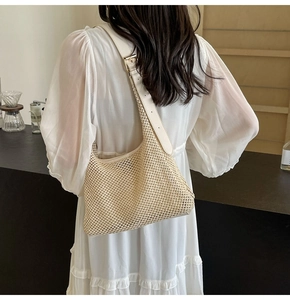 Dettaglio borsa a spalla in paglia intrecciata con tracolla in pelle beige e fibbia oro