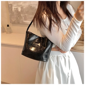 Détail d'un sac sous le bras en similicuir noir brillant avec texture huilée vintage