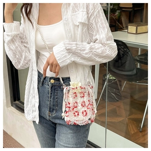 Detailed close-up of handmade red and white beaded bucket bag with pearl strap