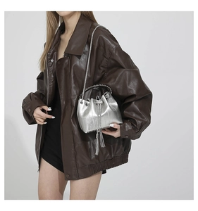Detail of silver PU bucket bag featuring fine texture, metal chain and long tassels