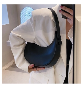 Detail of minimalist black leather hobo bag worn with a white blazer for a chic look