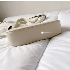 Detail view of the beige leather shoulder bag showing precise stitching and bottom structure