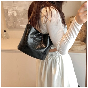 Détail du sac à épaule en similicuir noir brillant avec une texture vintage froissée