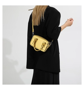 Detail of metallic gold PU leather crossbody bag worn by model in black suit