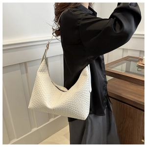 Close-up of white woven PU leather handbag shown on model in a minimalist setting