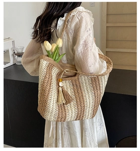 Detail of woven tote bag featuring bicolor stripes and a decorative tassel with yellow beads
