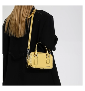 Mirror gold crossbody bag detail on black coat with silver metal hardware and strap
