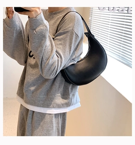 Detailed side view of a minimalist black crescent shoulder bag with a matte leather finish