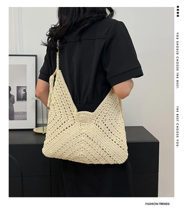 Detailed close-up of a beige crochet tote bag featuring bohemian tassels and hollow knit