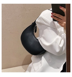 Mirror selfie showing the black leather crescent underarm bag with minimalist zipper design