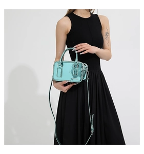 Detail of metallic mint green PU leather crossbody bag worn with a black dress