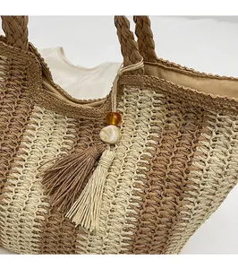 Detail of woven straw handbag featuring brown stripes, fringe charms and beaded accents