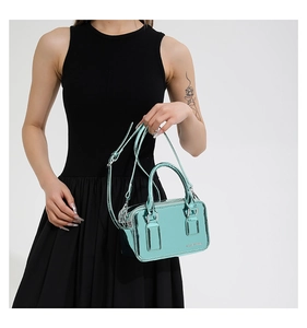 Detail view of metallic mint green crossbody bag with dual handles and brand embossing