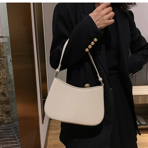 Detail view of cream white leather shoulder bag with smooth texture and silver hardware