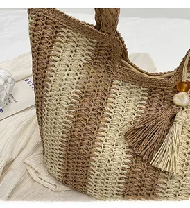 Detailed macro view of V-shaped woven straw handbag with tassels and marbled beads