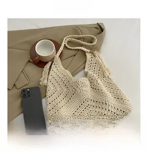 Close-up of cream knit shoulder bag showing V-pattern crochet texture and tassels