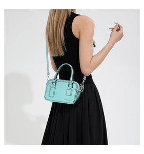 Detail view of mint green PU leather mini crossbody bag with metallic logo and thin strap