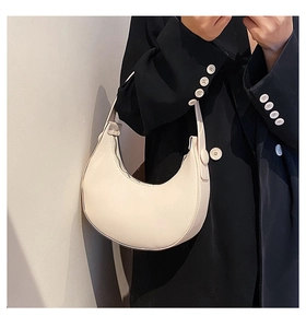Detailed view of cream-colored crescent hobo bag made of matte vegan leather material
