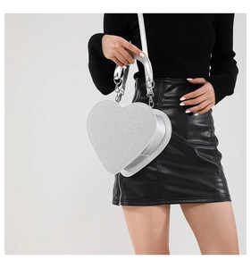 Détail du sac coeur pailleté argenté avec poignée métallique et chaîne sur tenue noire