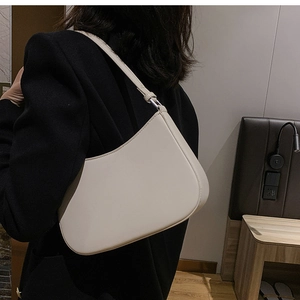 Minimalist cream white crescent shoulder bag shown on shoulder in a stylish interior