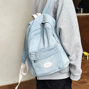 Minimalist light blue denim backpack with MUJIU logo label and white adjustable straps