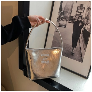 Détail du sac seau métallisé argenté avec texture plissée et effet miroir poli