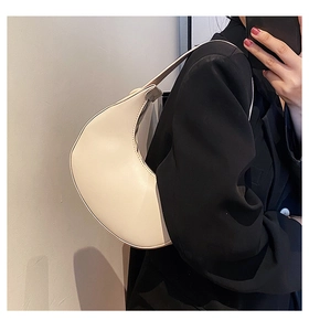 Close-up of a cream-colored leather crescent underarm bag worn over the shoulder