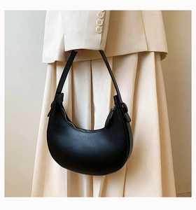 Close-up of a black matte PU leather hobo bag worn by a model in a beige suit