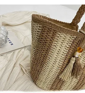 Detail of woven tote bag featuring beige brown stitching and tassel bead decoration