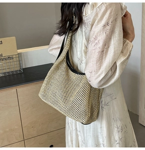 Dettaglio della borsa hobo in paglia intrecciata con spalline in pelle nera