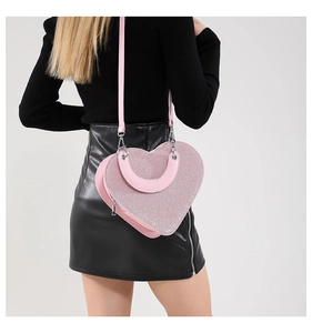 Détail d'un sac pailleté rose en forme de cœur montrant la texture et la chaîne en métal