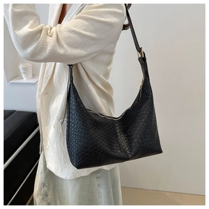 Detail of minimalist black PU leather crossbody bag featuring a textured woven pattern surface