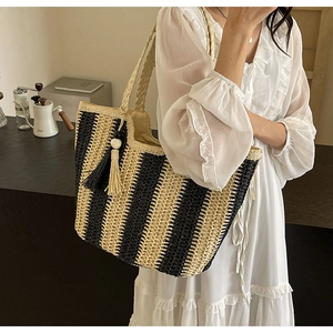 Chic woven tote bag with yellow and black stripes worn by model in minimalist setting