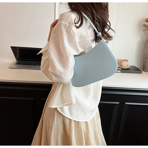 Minimalist light blue leather underarm bag with an elegant curved shape for women