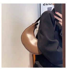Close-up of a brown matte leather half-moon shoulder bag with a minimalist design