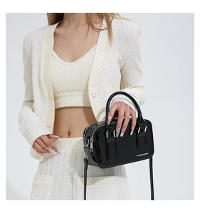Close-up of black patent leather handbag with fashion lettering and polished handles