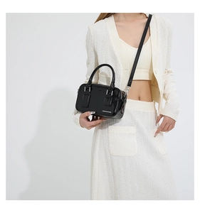 Close-up of black glossy PU leather handbag with white Fashion & Bags text on white outfit