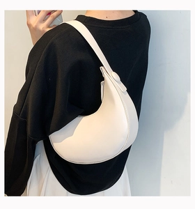 Detail view of a white PU crescent underarm bag styled on a casual black hoodie