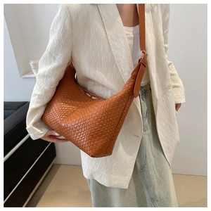 Close-up of woven caramel brown leather hobo bag with gold buckle and adjustable strap