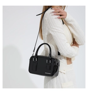 Close-up of a glossy black PU leather crossbody bag with silver hardware and fashion text