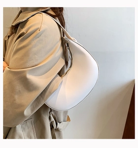 Detailed view of white PU leather crescent shoulder bag with fine stitching on model