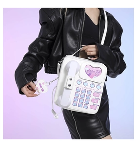 Close-up of retro white telephone handbag with heart window and heart-shaped keychain
