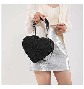 Détail macro du sac à main cœur en paillettes noires avec chaîne et poignée en cuir