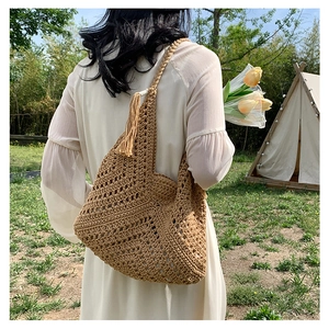 Detail of bohemian khaki knit tote bag with tassel accent during outdoor camping