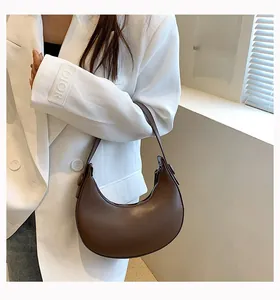 Detailed close-up of brown crescent underarm bag with matte leather and metal zipper