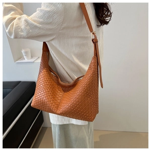 Detailed close-up of woven texture and adjustable strap on a stylish orange PU shoulder bag
