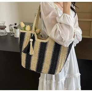 Detail of woven straw tote bag with black and white stripes and tassel decoration