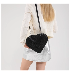 Détail du sac à main noir en forme de cœur avec paillettes porté par un mannequin